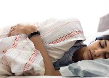 Alta HR lifestyle shot featuring a young Indian woman wearing the black classic band while sleeping.