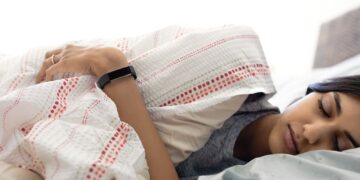 Alta HR lifestyle shot featuring a young Indian woman wearing the black classic band while sleeping.