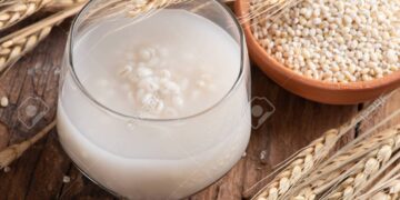 Barley water in glass with raw and cooked pearl barley wheat/seeds.