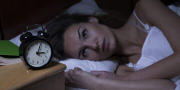 Woman with insomnia lying in bed with open eyes