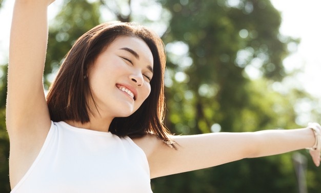 close up asian woman stretching hands up smiling walking park looking carefree happy 197531 22528