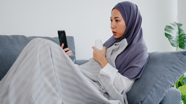 young muslim lady wear hijab using phone video call talking with doctor consultation online consultation sofa living room home 7861 3004