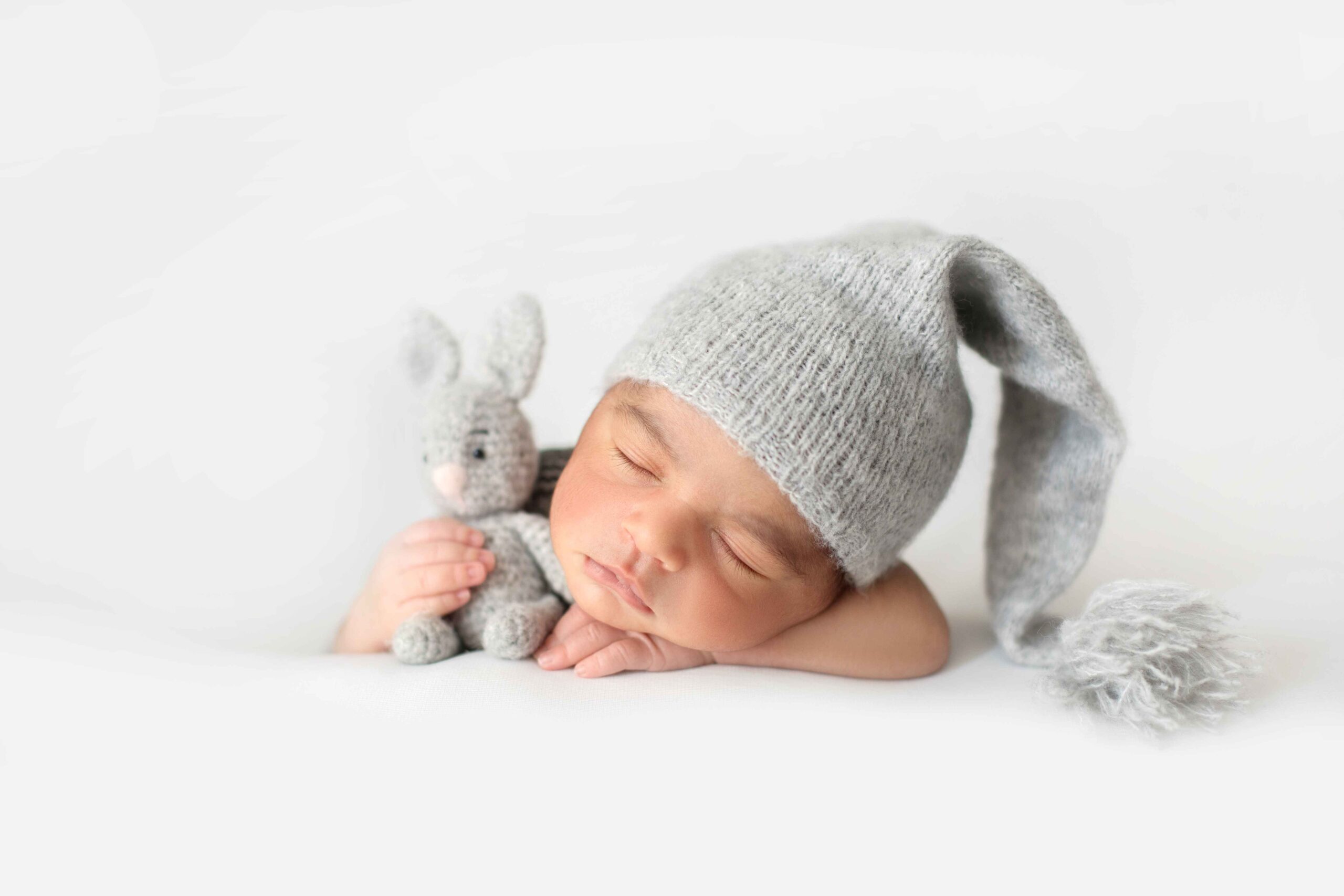 cute infant sleeping with grey crocheted hat with toy rabbit 11zon scaled