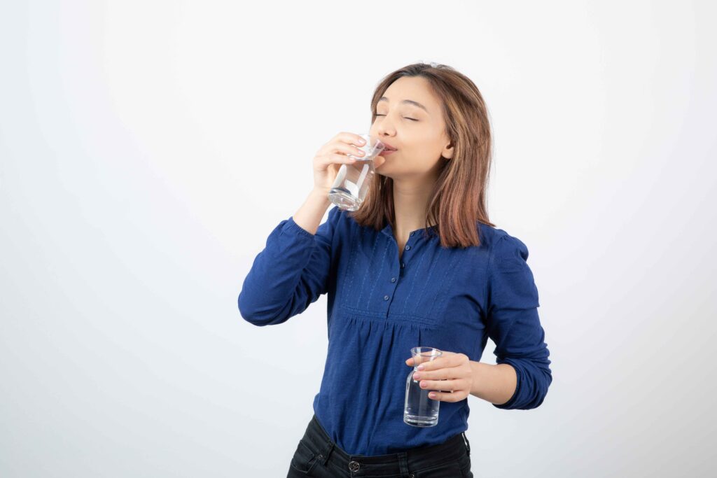 young girl blue blouse drinking glass water white wall 11zon